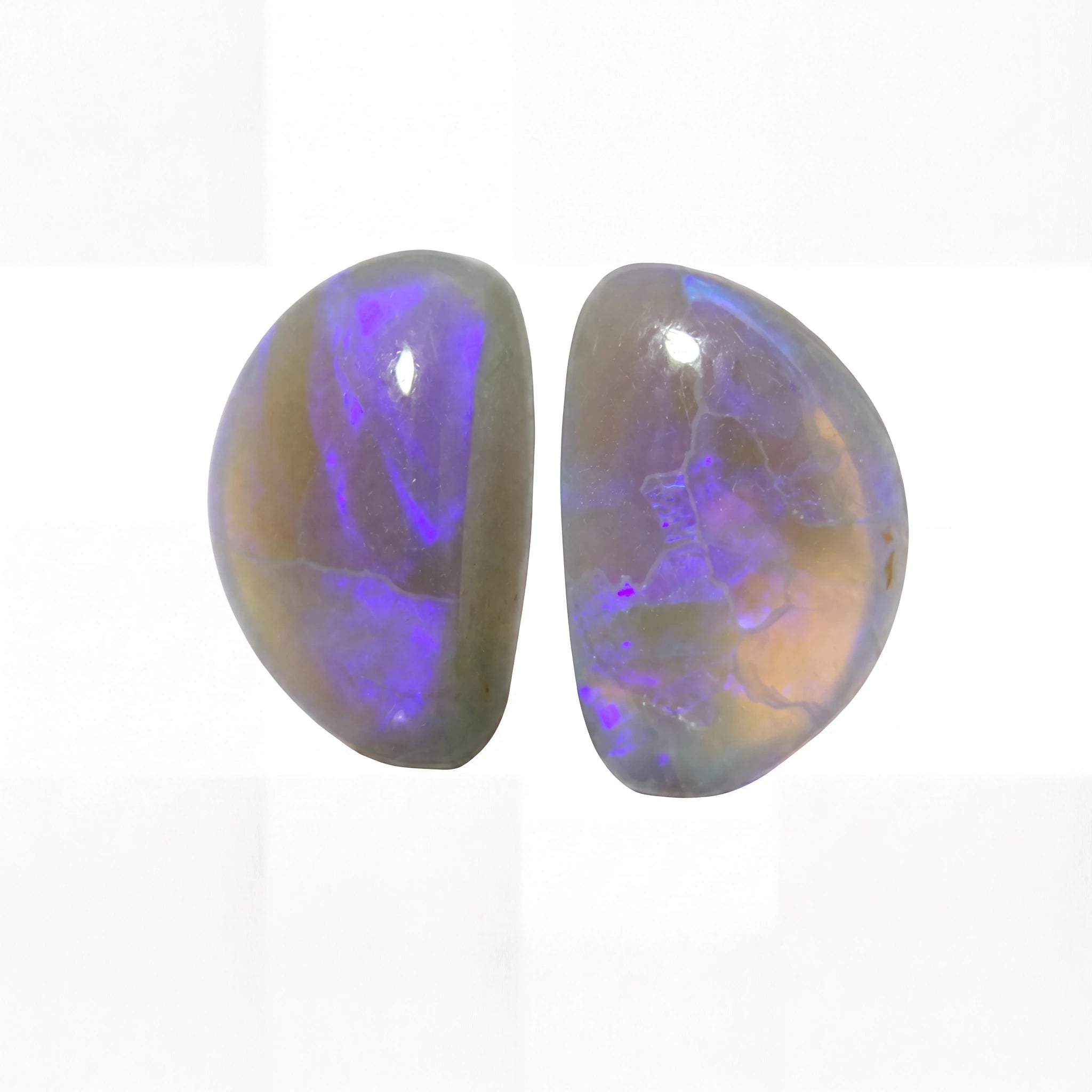 Two polished oval cabochon gemstones showing vibrant purple and blue iridescent play-of-colour over a warm beige-brown base, set against a clean white background.