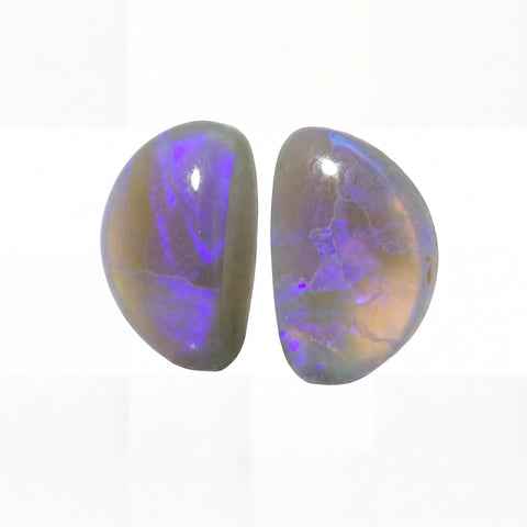 Two polished oval cabochon gemstones showing vibrant purple and blue iridescent play-of-colour over a warm beige-brown base, set against a clean white background.