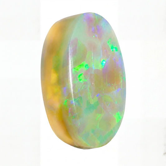 A polished oval cabochon gemstone showing a play-of-colour opal pattern with vibrant green, blue, purple, and yellow iridescence over a pale base, set against a plain white background.