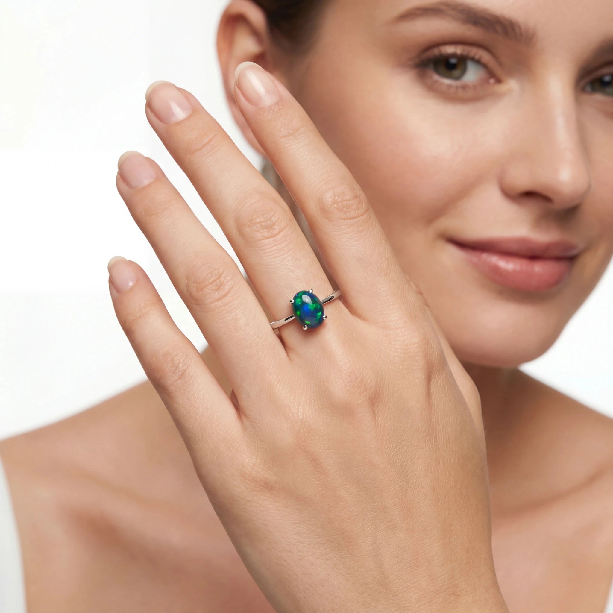 Woman wearing a ring with a green gemstone on a white background