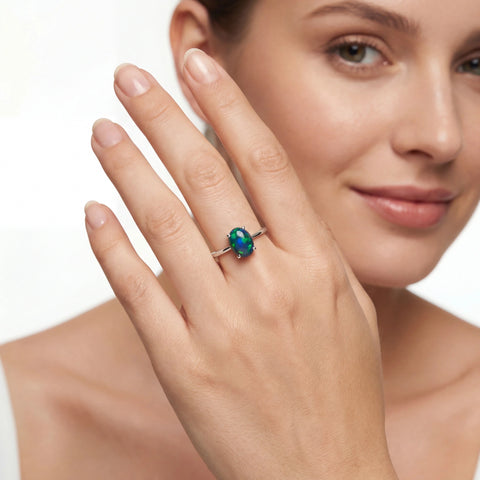 Woman wearing a ring with a green gemstone on a white background