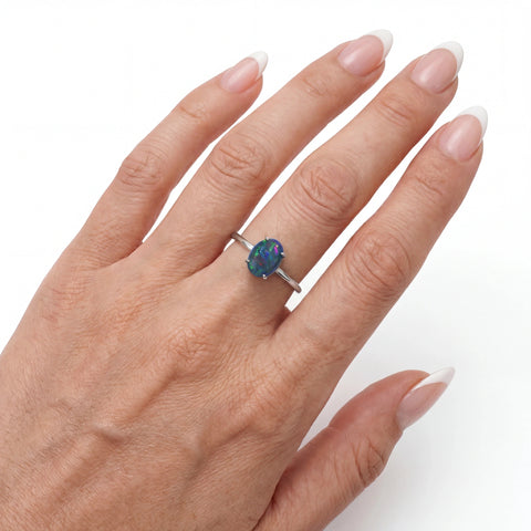 Hand wearing a ring with an opal stone on a white background