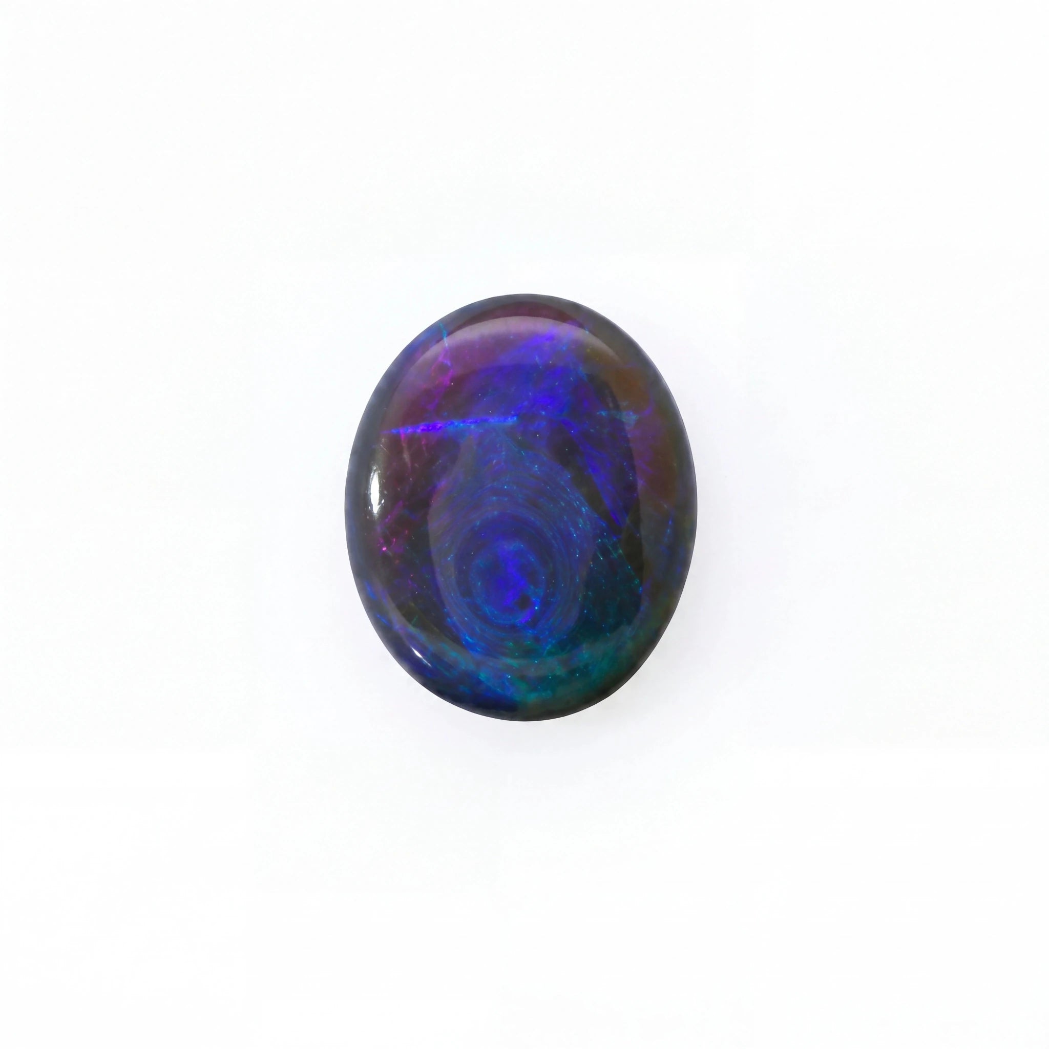 A polished oval cabochon gemstone displaying vibrant iridescent play-of-colour with swirling patterns of blue, purple, and green on a white background.