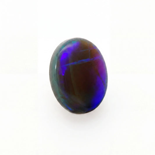A polished oval cabochon gemstone displaying vibrant iridescent play-of-colour with deep blue, purple, and green hues over a dark brown base, set against a plain white background.
