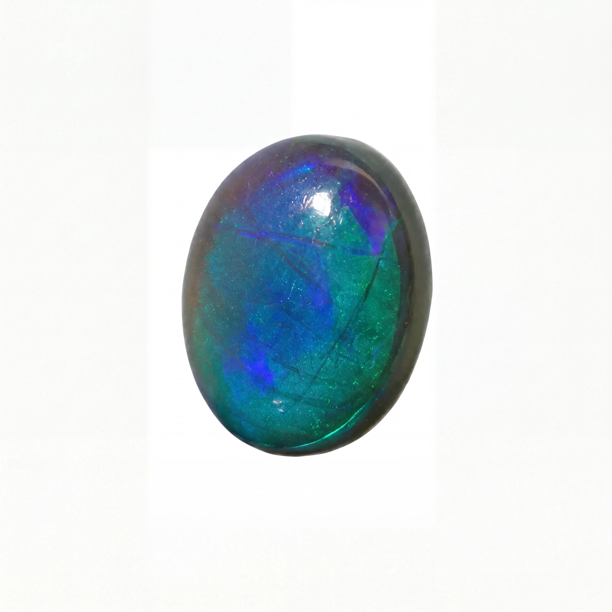 A polished oval cabochon gemstone showing vibrant iridescent colours of blue, green, and purple on a white background.