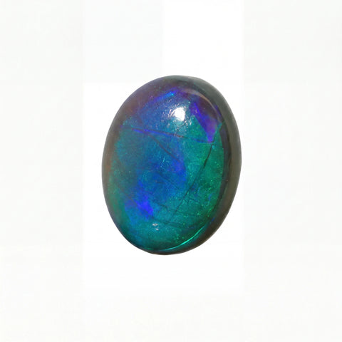 A polished oval cabochon gemstone showing vibrant iridescent colours of blue, green, and purple on a white background.