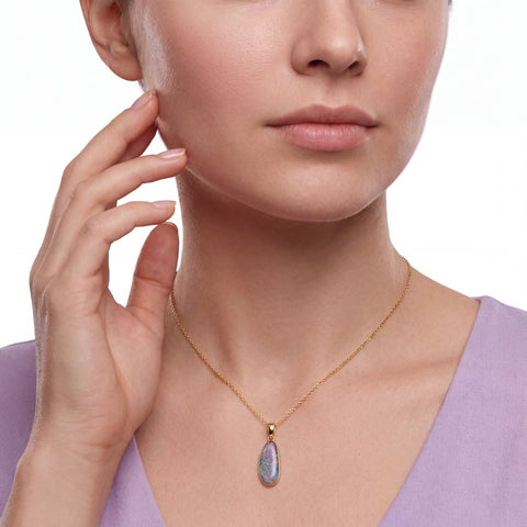 Close-up of a woman wearing a gold necklace with a pendant on a white background