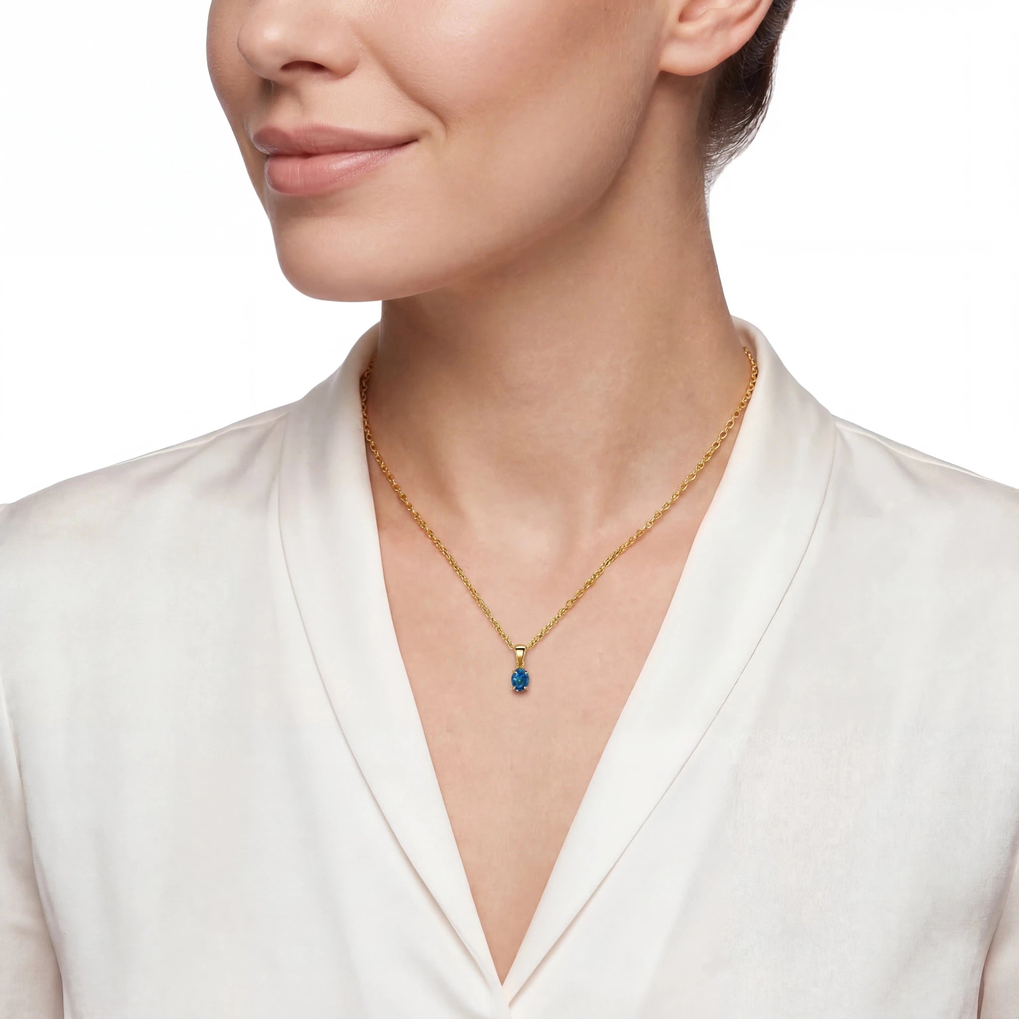Woman wearing a gold necklace with a blue pendant on a white background