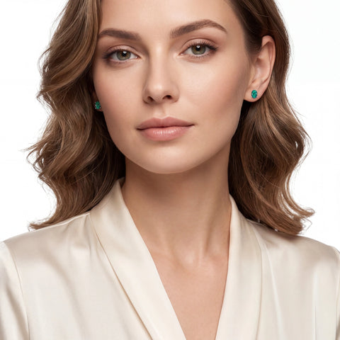 Woman wearing green earrings with a plain background