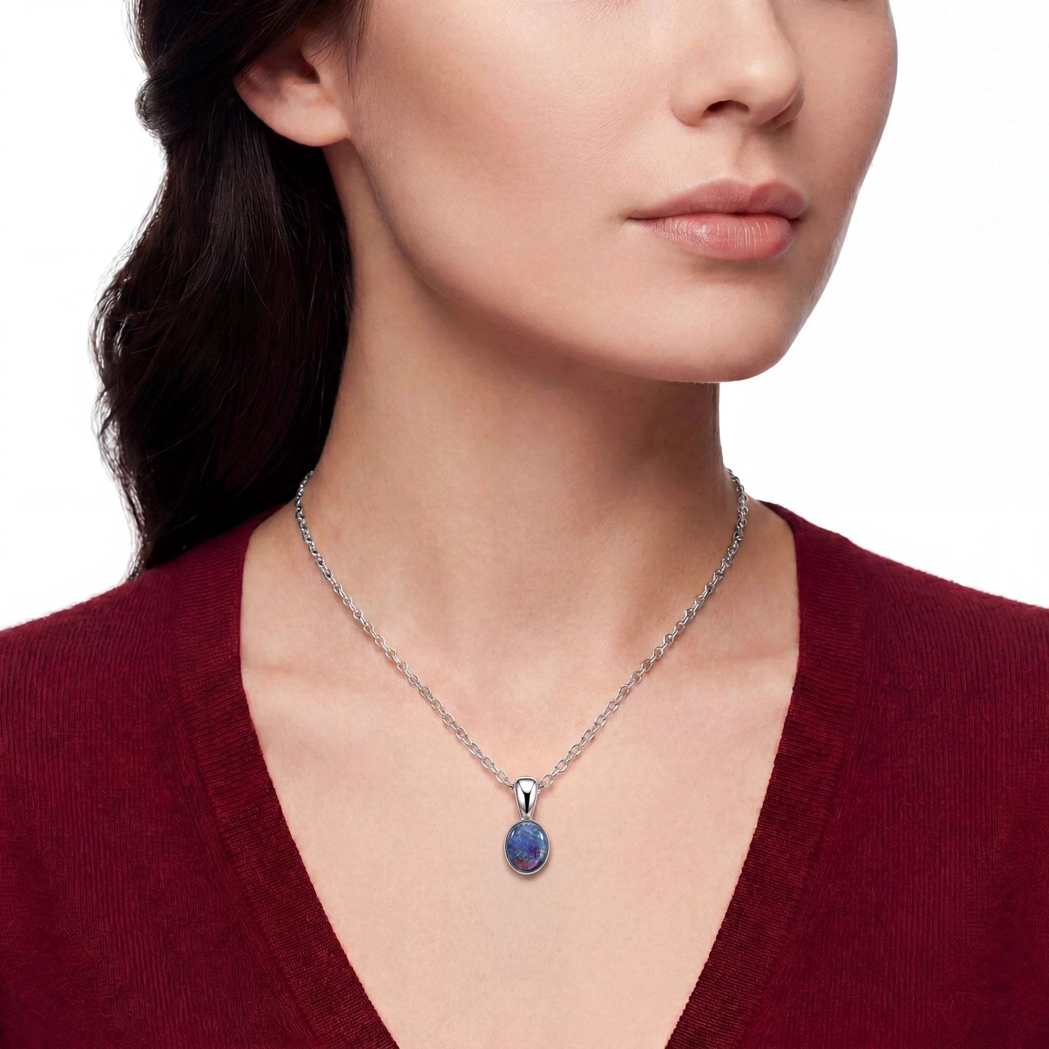 Woman wearing a silver necklace with a blue pendant on a white background