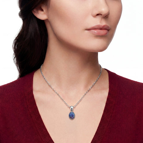 Woman wearing a silver necklace with a blue pendant on a white background