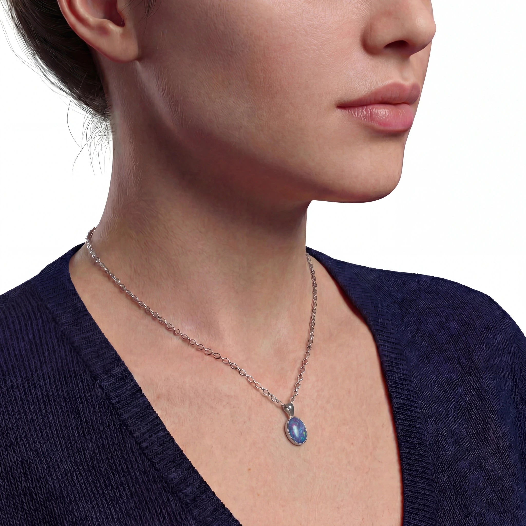 Close-up of a necklace with a blue pendant on a person wearing a dark blue top.
