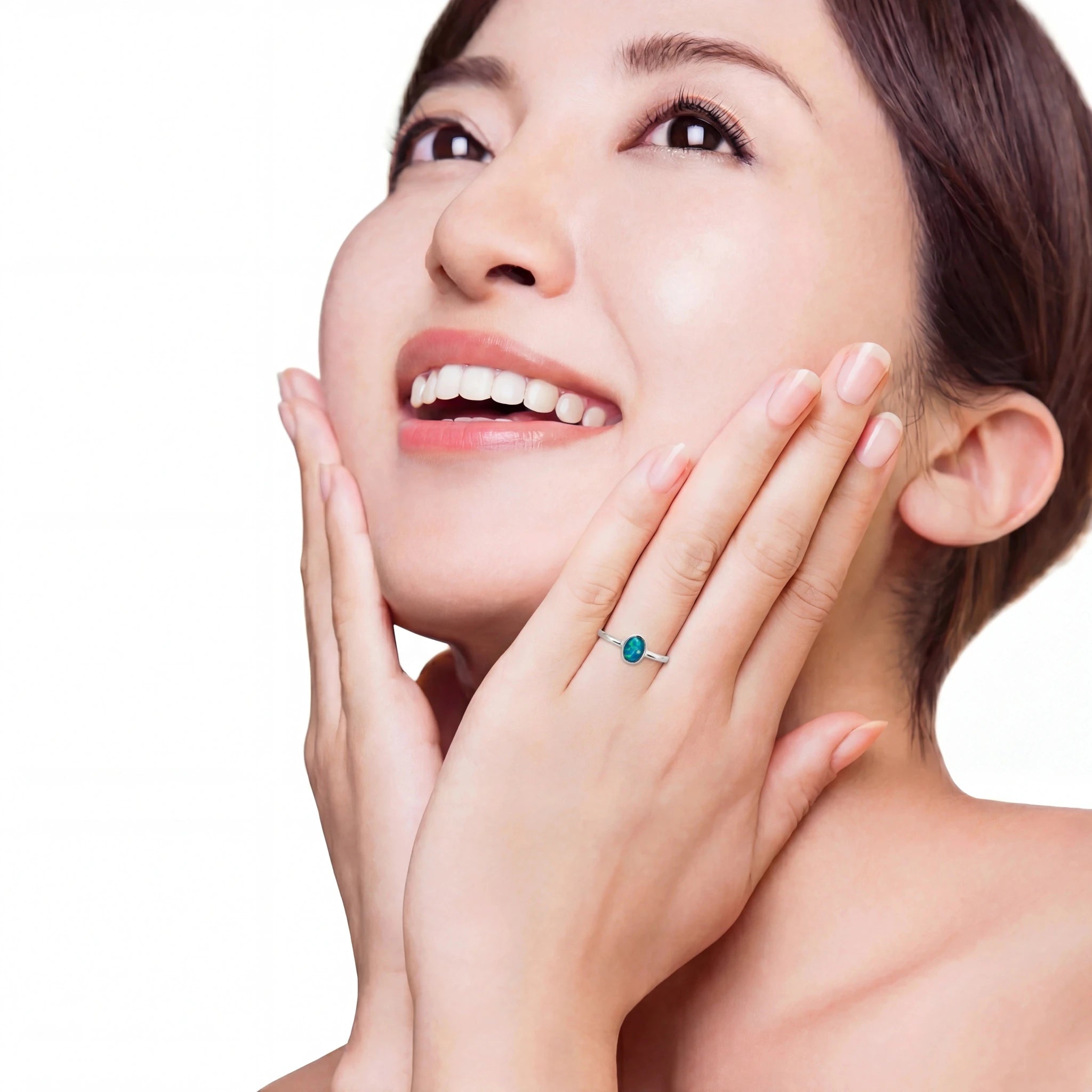 Woman with a ring on her finger touching her face against a white background