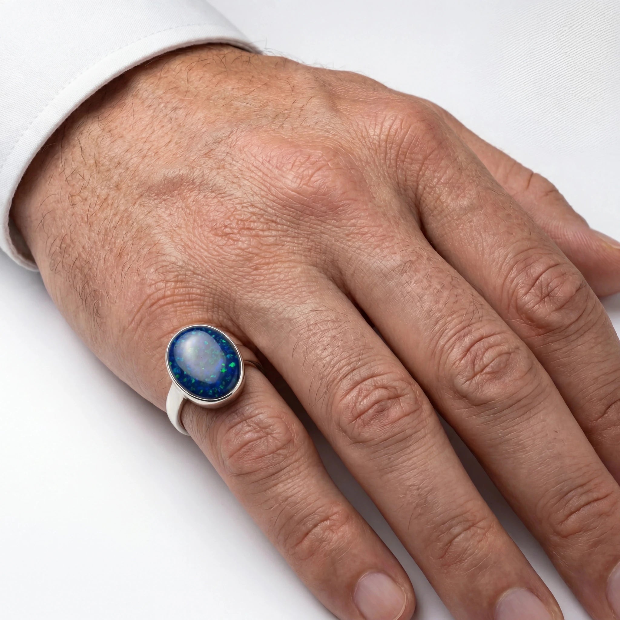 Hand wearing a ring with a blue gemstone on a white background