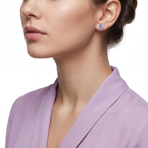 Close-up of a woman wearing a lavender top and opal earrings with a white background