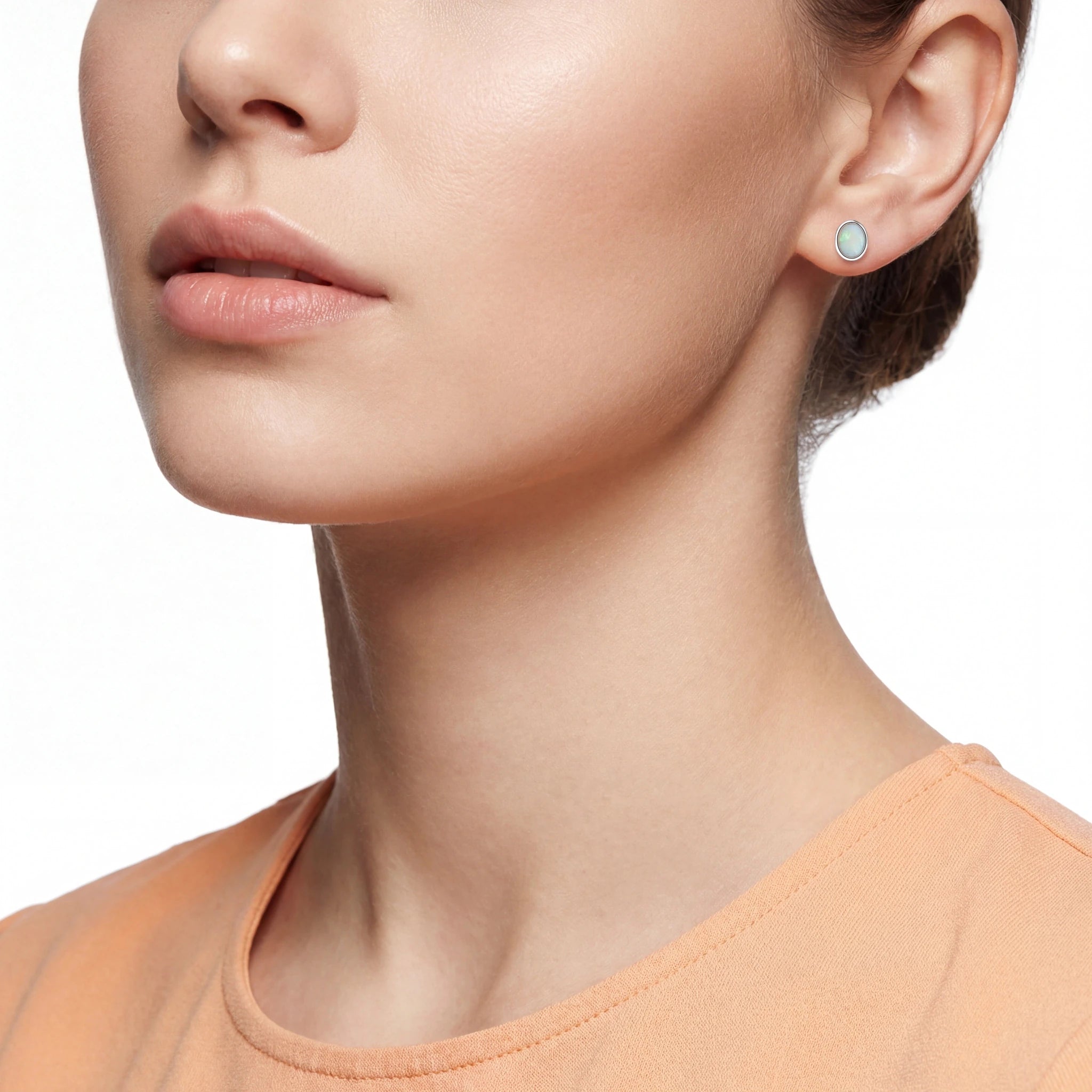 Close-up of a woman wearing a round opal earring on a white background
