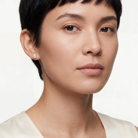 Close-up of a woman wearing a gold opal earring on a white background
