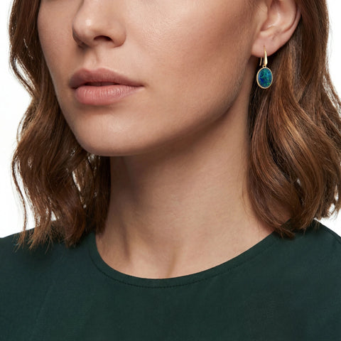 Close-up of a person wearing a green earring with a white background