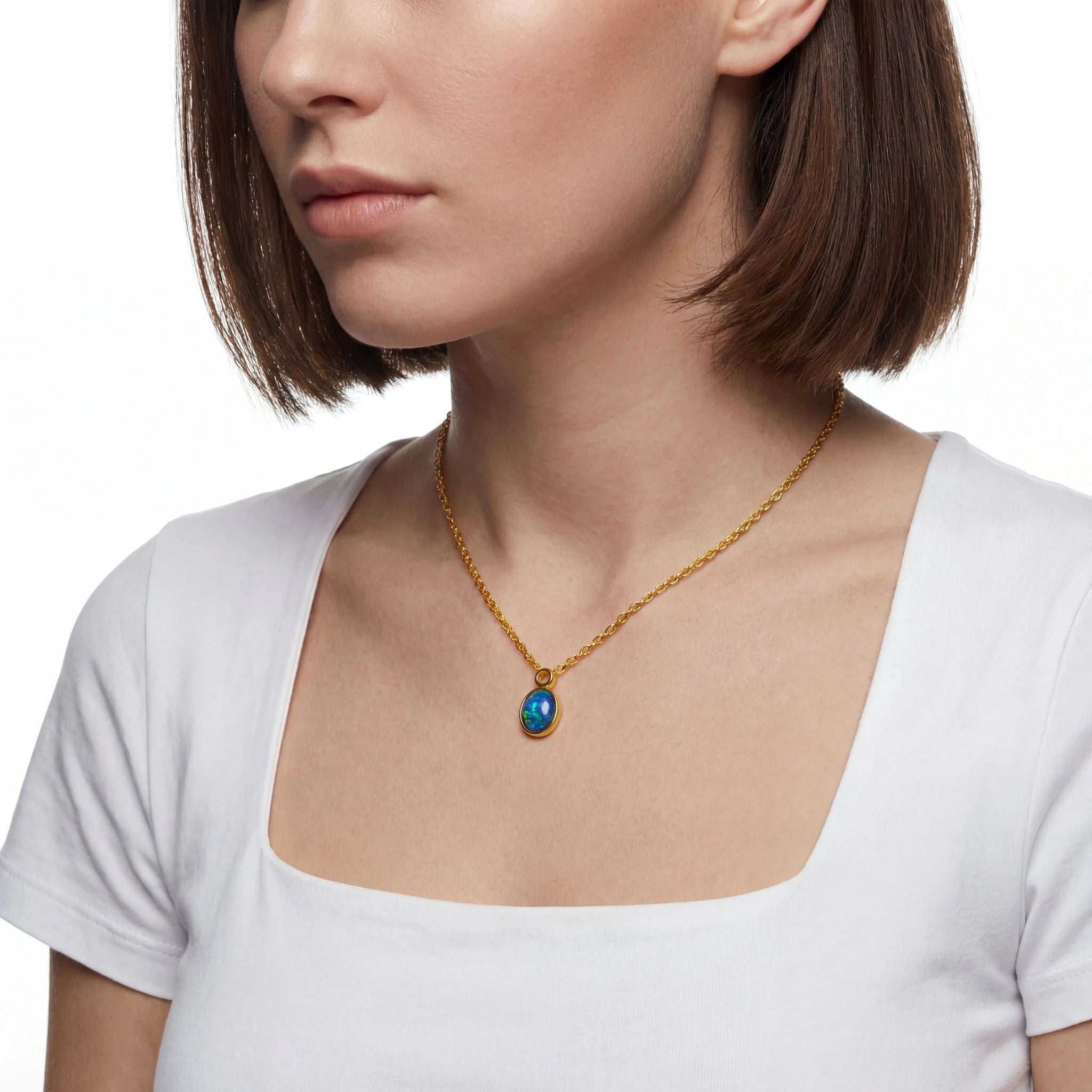 Close-up of a person wearing a gold necklace with a blue pendant on a white background