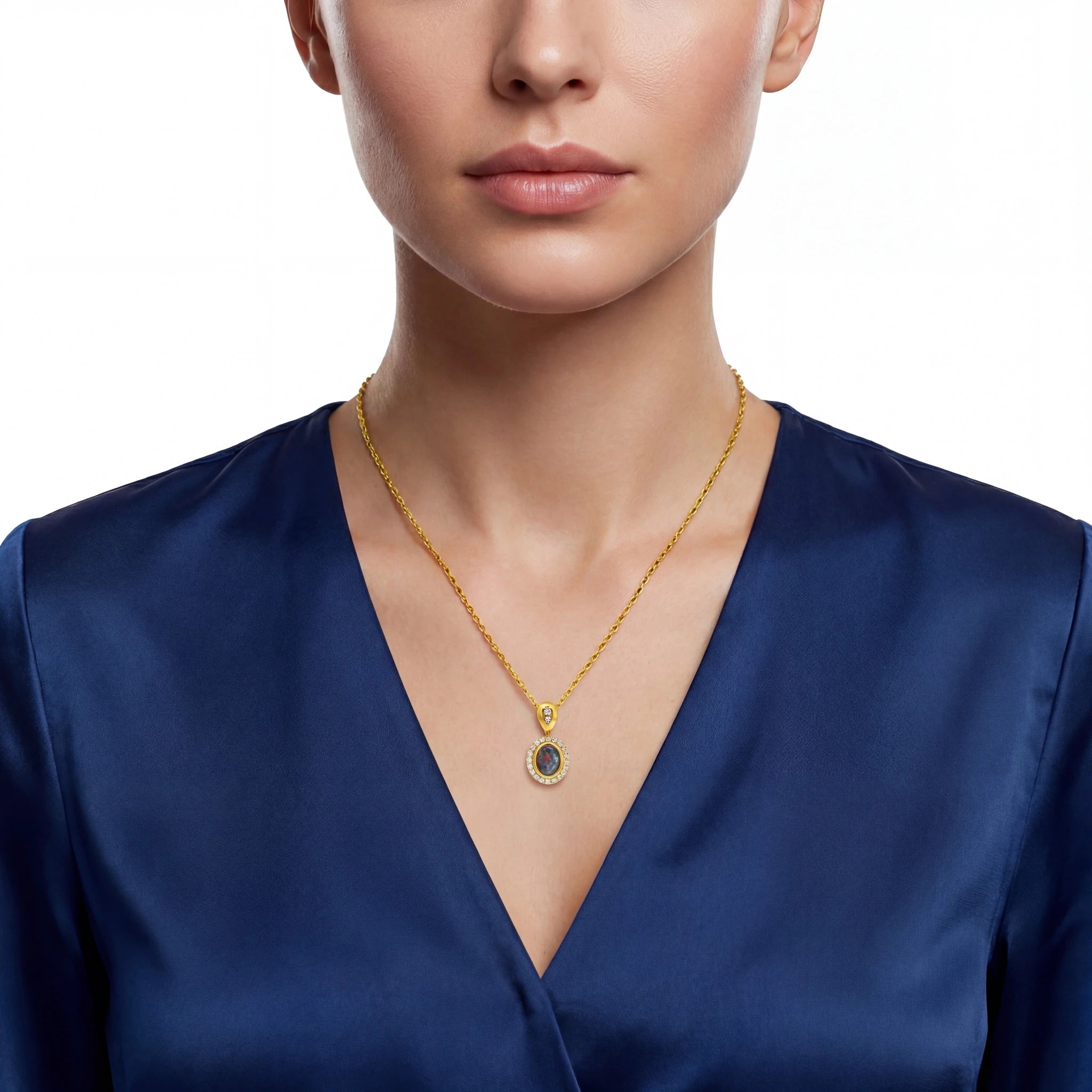 Gold necklace with a pendant on a person wearing a blue top against a white background