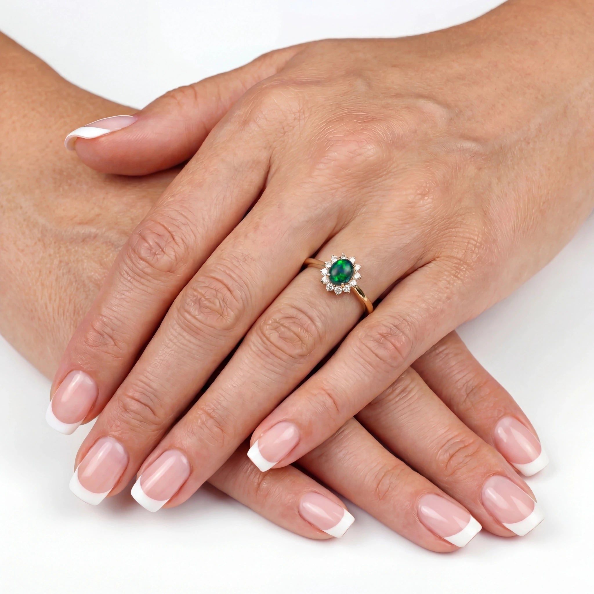 Close-up of a hand wearing an emerald ring on a white background