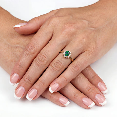 Close-up of a hand wearing an emerald ring on a white background