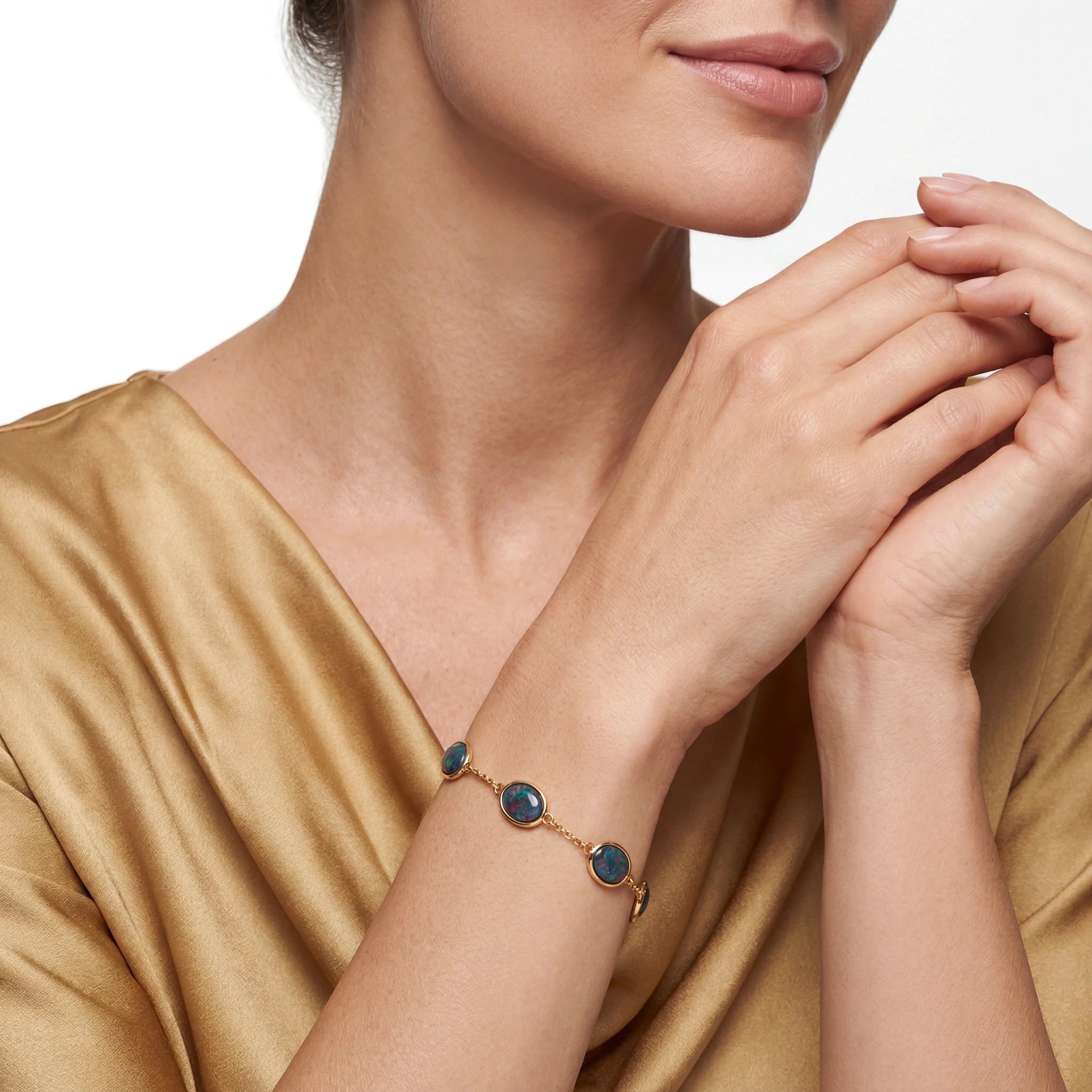 Woman wearing a gold bracelet with blue stones on a plain background