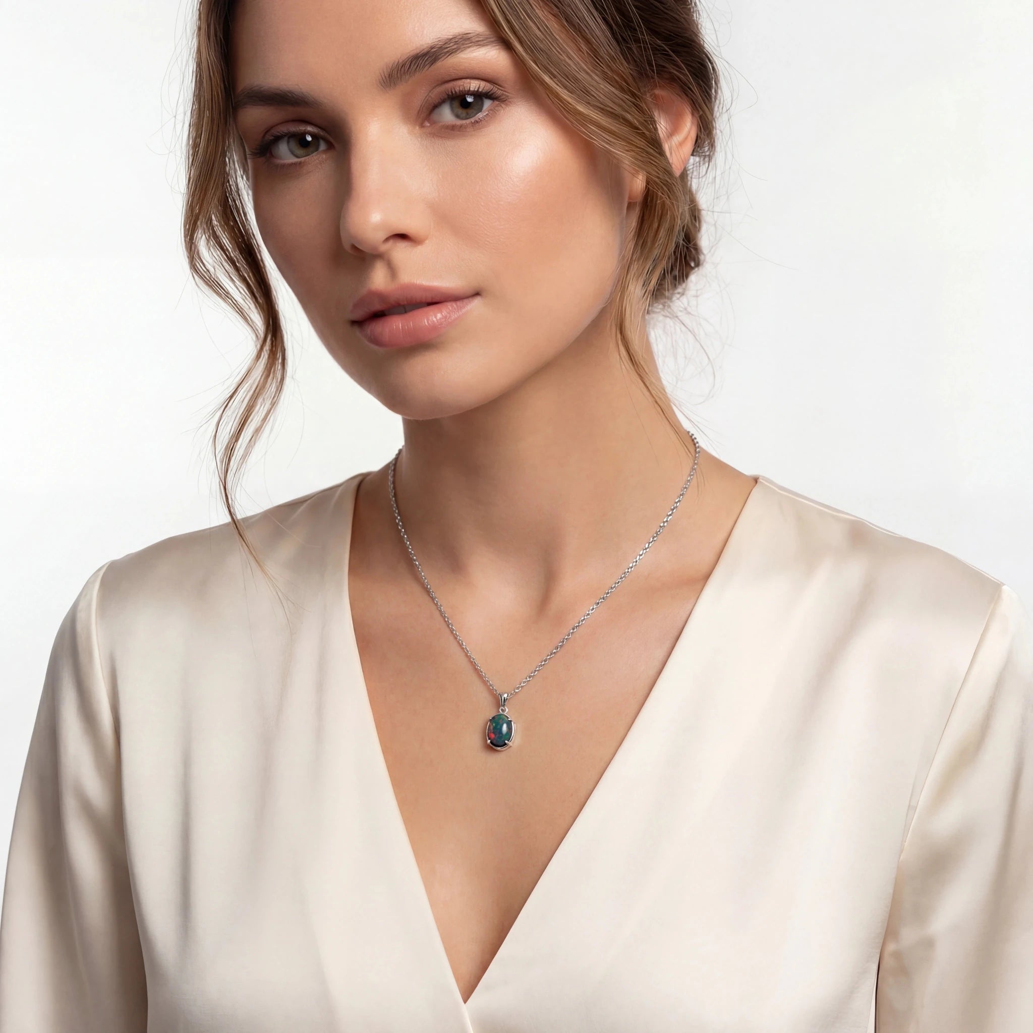 Woman wearing a necklace with a pendant on a plain background