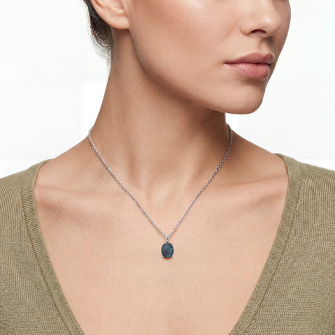Close-up of a woman wearing a necklace with a green pendant on a white background