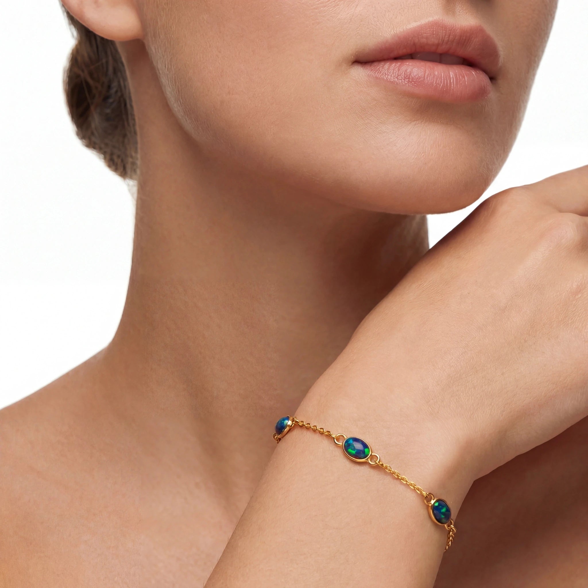 Gold bracelet with green gemstones on a person's wrist, close-up view.