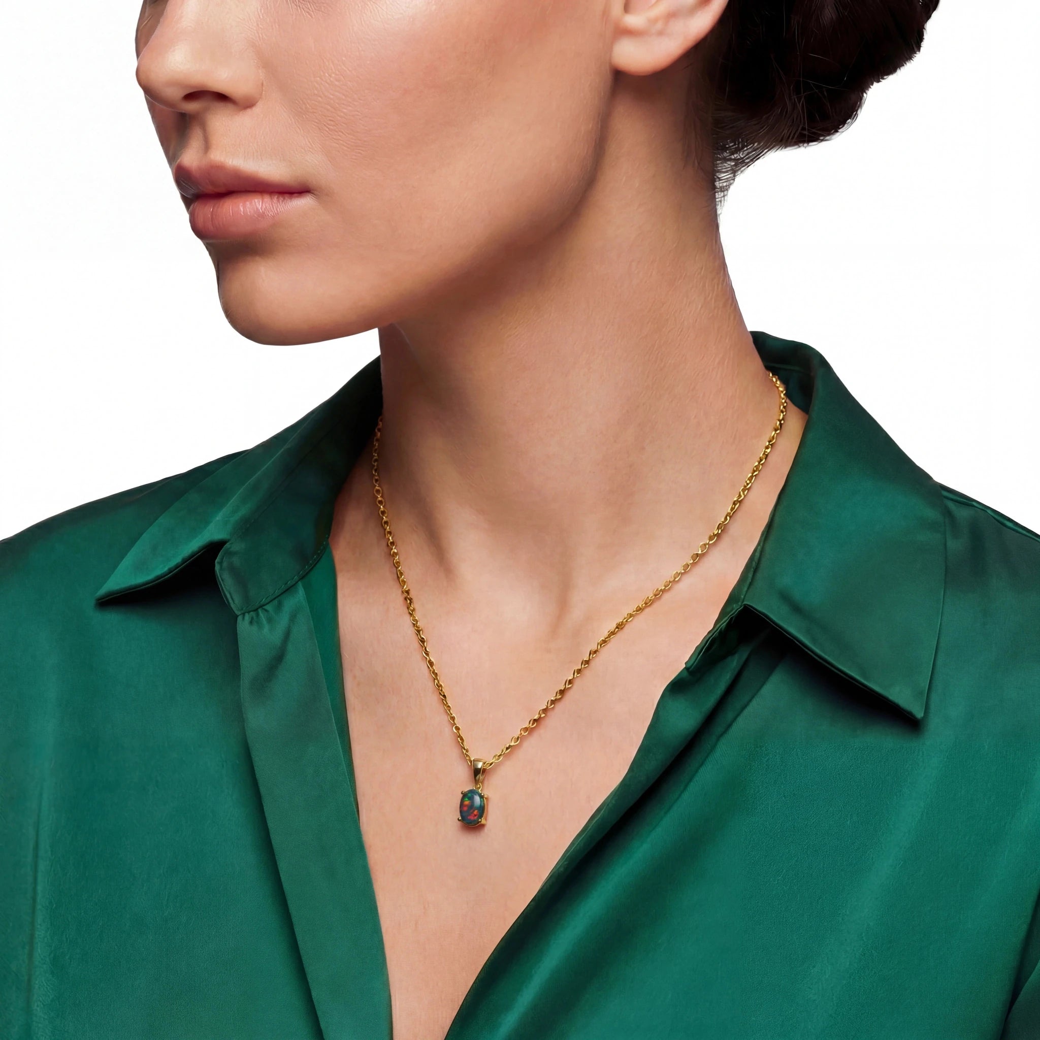 Woman wearing a gold necklace with an opal pendant against a white background