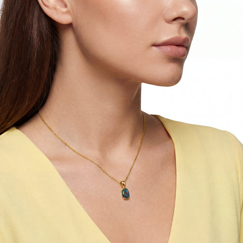 Close-up of a woman wearing a gold necklace with a green pendant on a white background