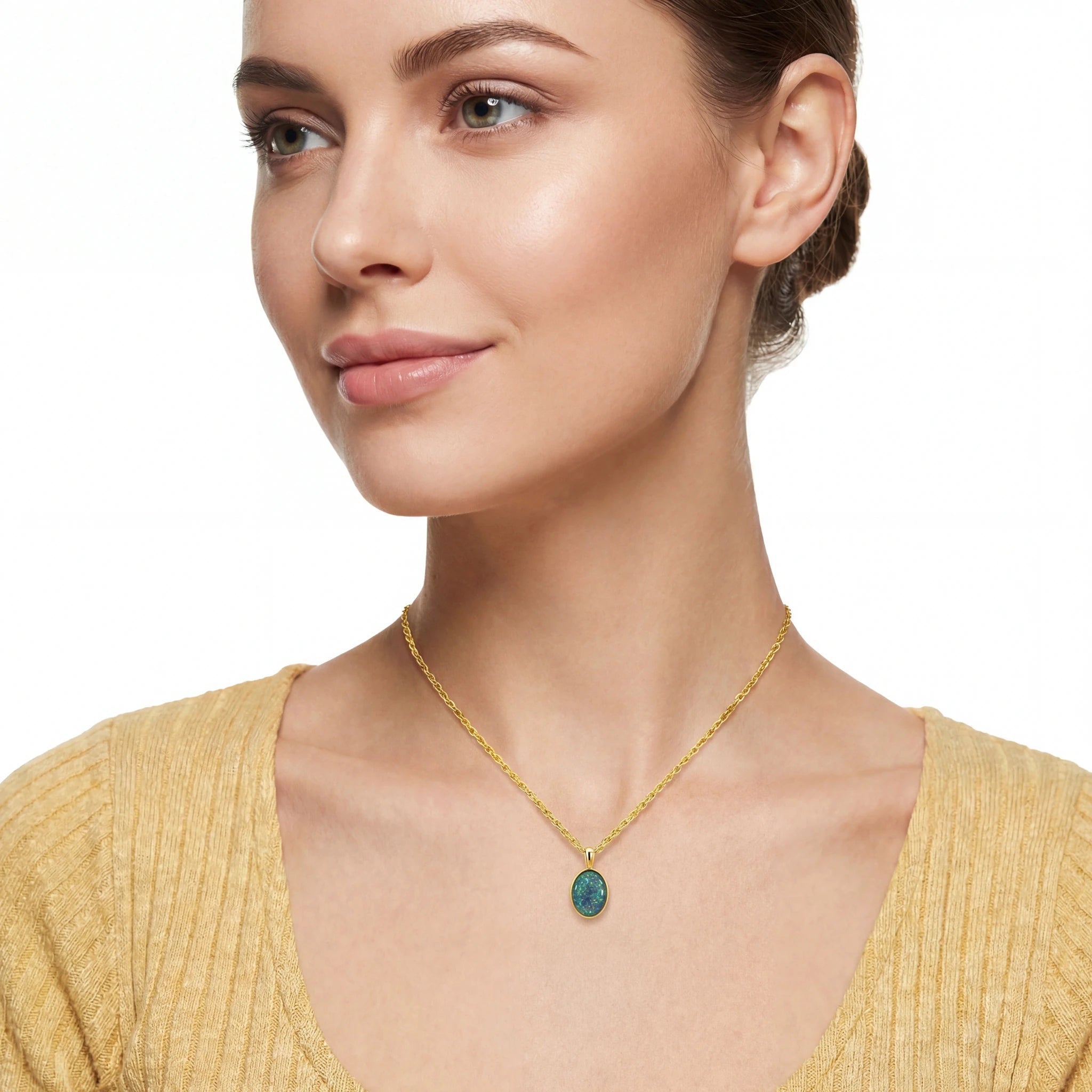 Woman wearing a gold necklace with a green pendant on a white background