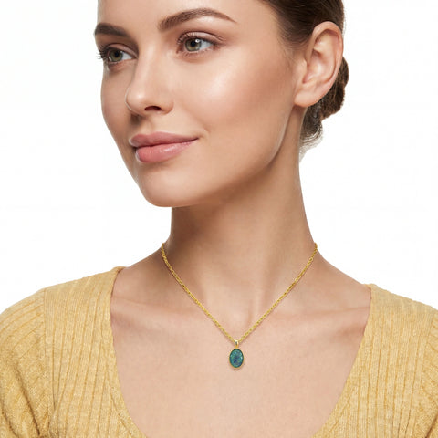Woman wearing a gold necklace with a green pendant on a white background
