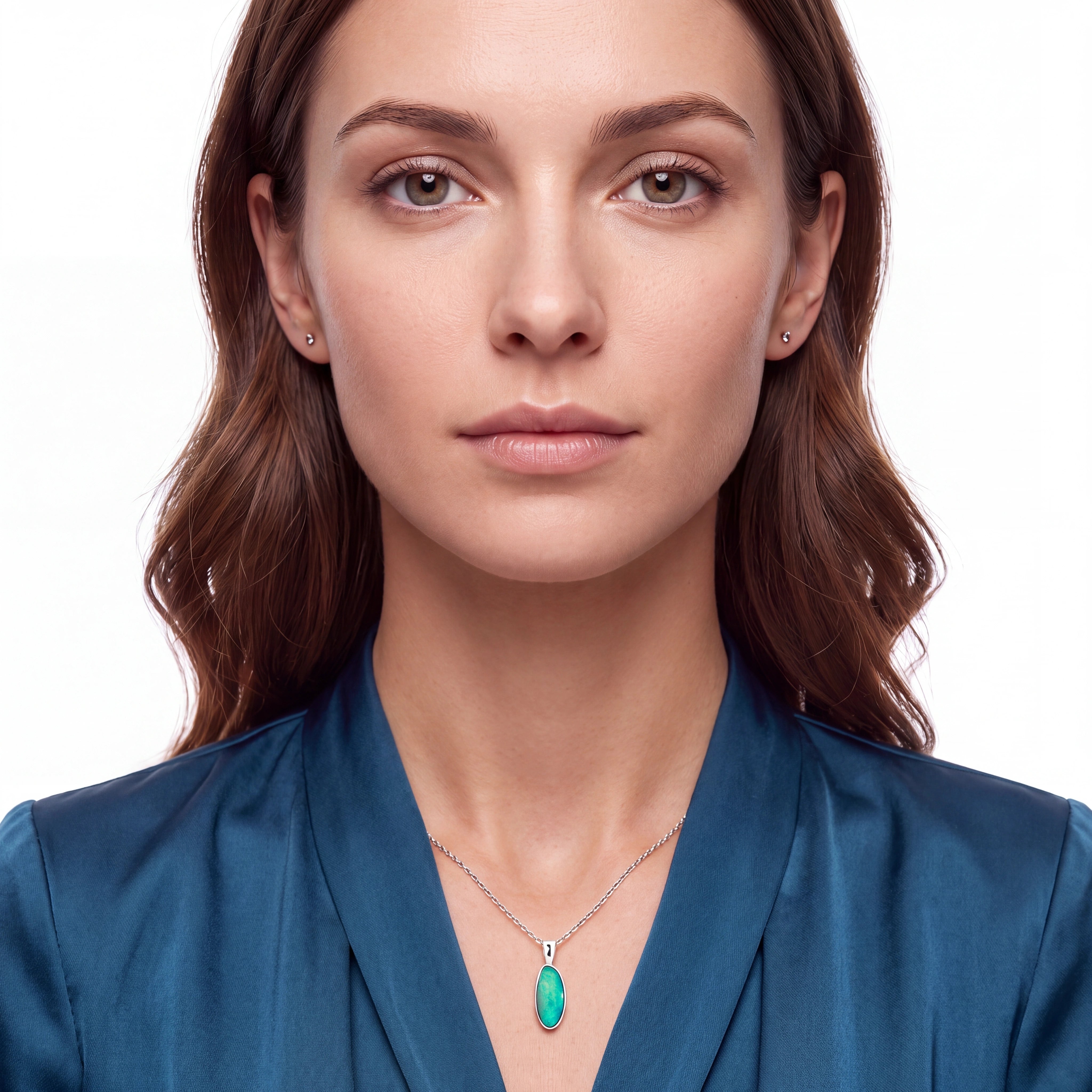 A close-up portrait of a woman wearing a delicate silver chain necklace with a vibrant green oval pendant, set against a clean white background.