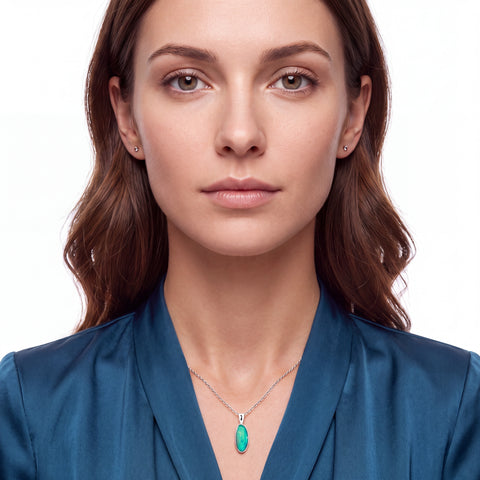 A close-up portrait of a woman wearing a delicate silver chain necklace with a vibrant green oval pendant, set against a clean white background.