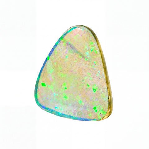 A triangular bezel-set opal gemstone with a gold-toned metal border, showcasing a play-of-colour pattern with vibrant green, blue, and pink flashes on a pale cream background, isolated on a white background.