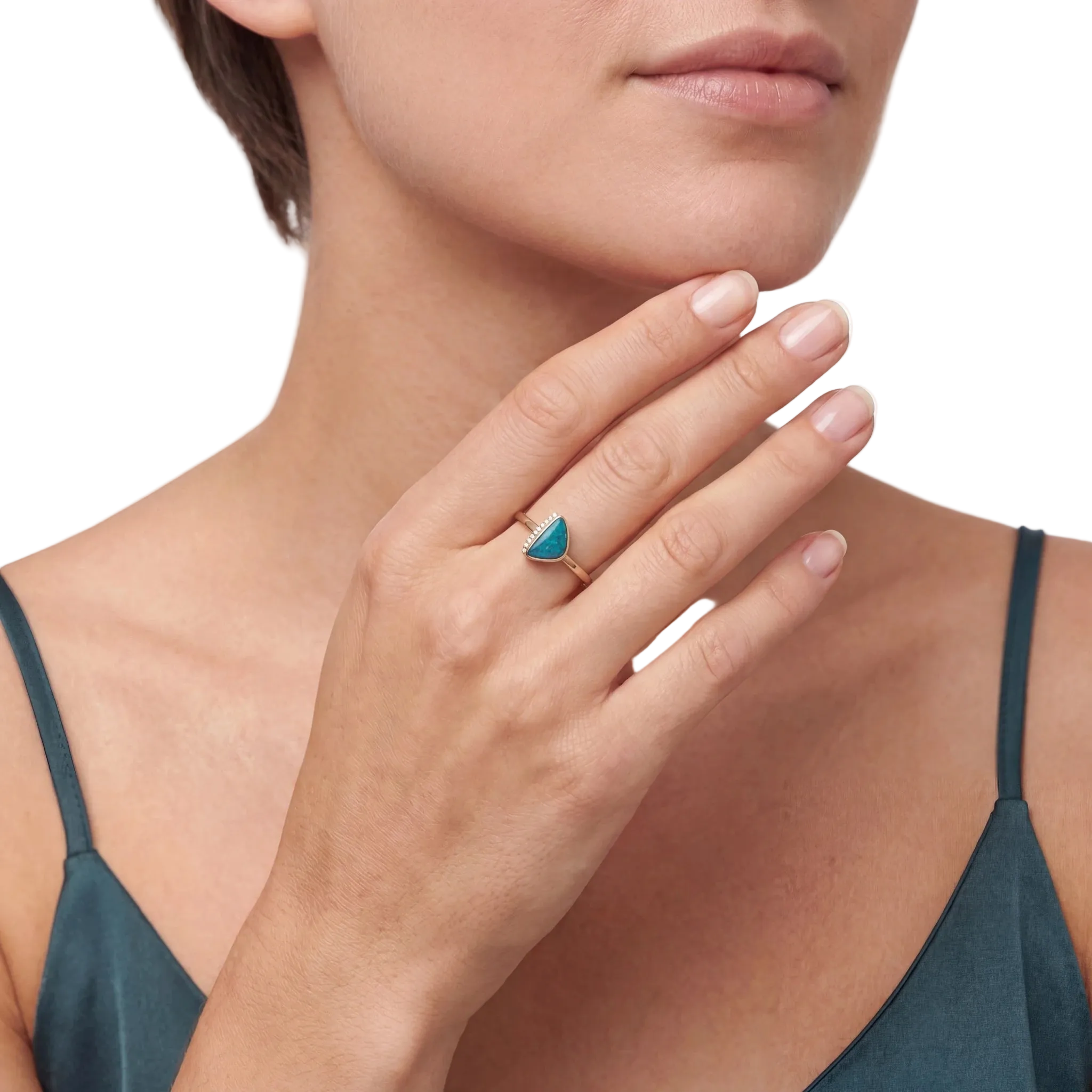 Close-up of a woman's hand wearing a turquoise opal gemstone ring on a white background