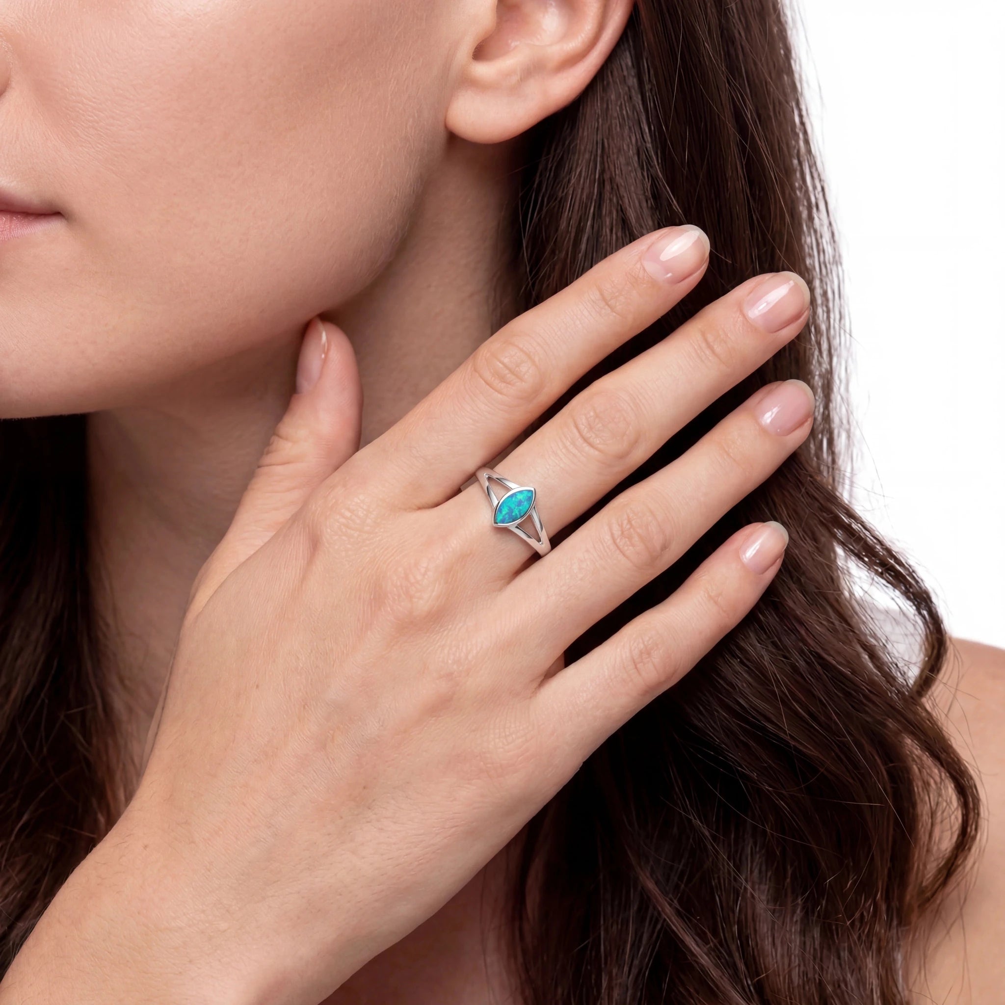 Woman wearing a silver ring with a blue gemstone on a neutral background