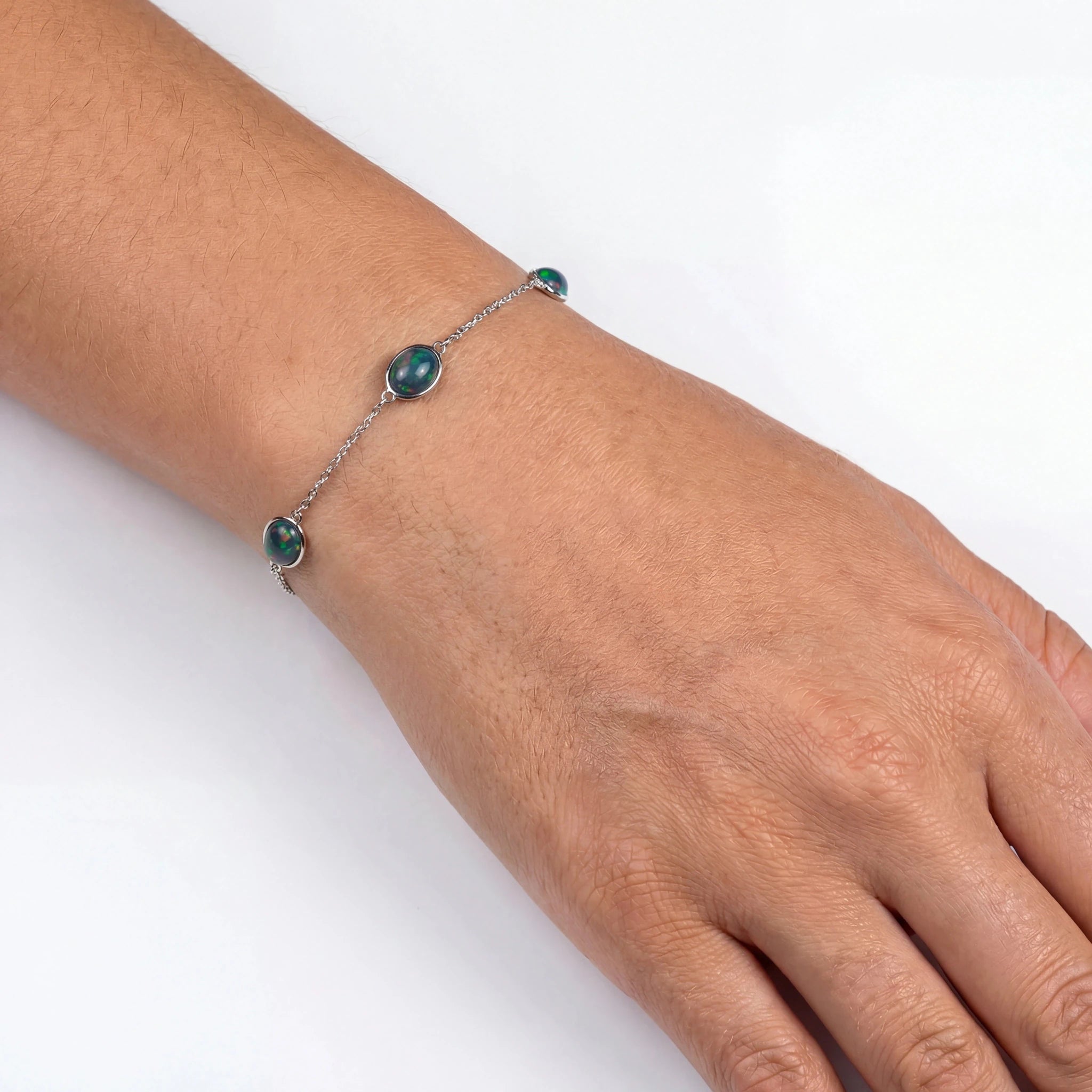 Bracelet with green beads on a wrist against a white background