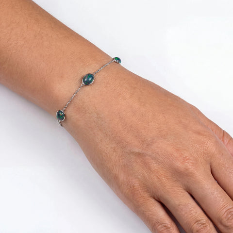 Bracelet with green beads on a wrist against a white background