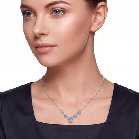 Woman wearing a necklace with blue gemstones on a plain background