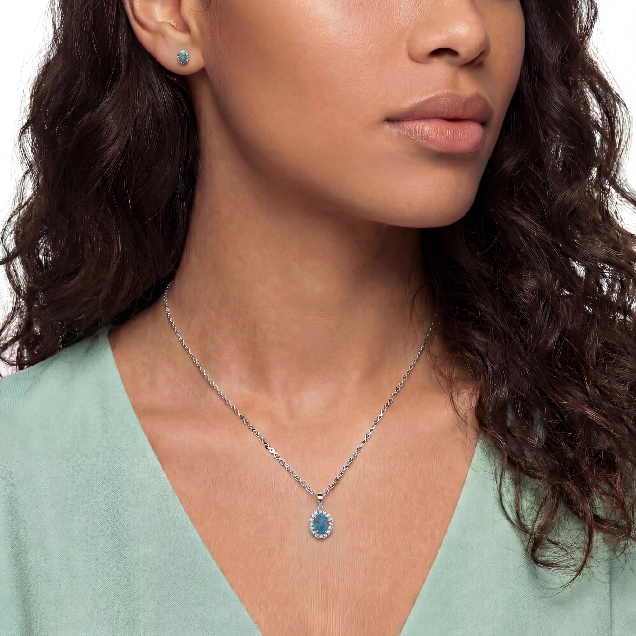 Woman wearing a necklace with a blue pendant on a plain background