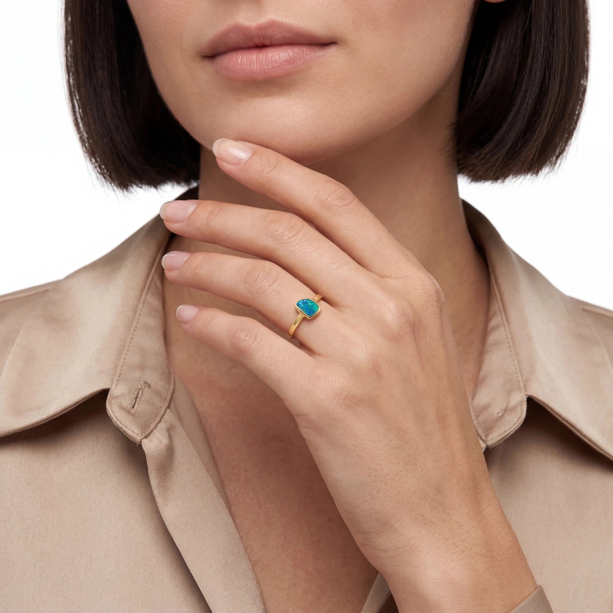 Close-up of a woman's hand wearing a gold ring with a blue opal gemstone