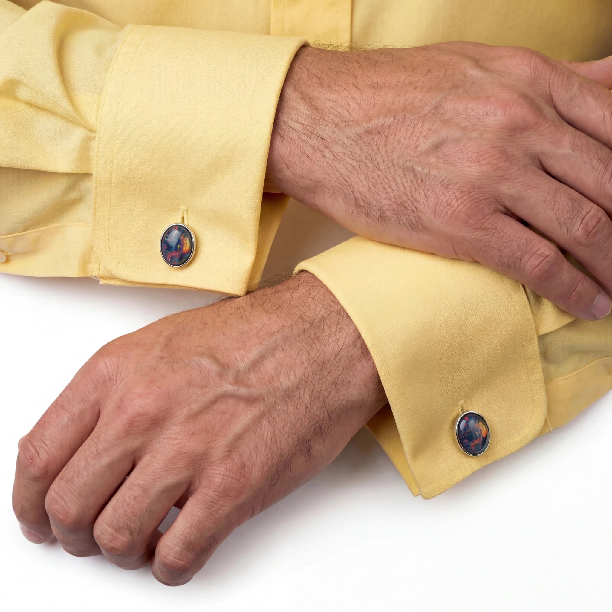Close-up of a person wearing a yellow shirt with cufflinks on a white background