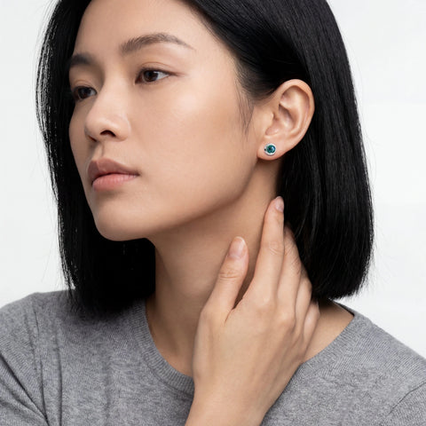Woman wearing a pair of earrings with a neutral background