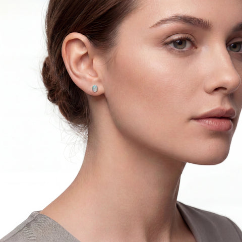 Close-up of a woman wearing a small round earring on a plain background