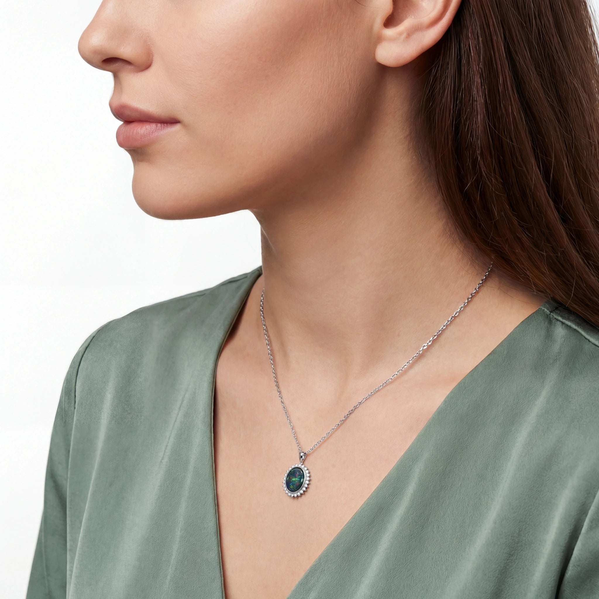 Close-up of a woman wearing a silver necklace with a green pendant on a white background