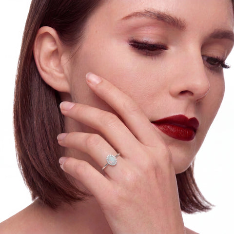 Close-up of a woman wearing an opal ring on a white background