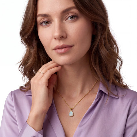 Woman wearing a gold necklace with a pendant on a white background